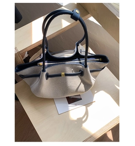 Close-up of canvas tote bag with contrast leather trim and white stitching detail