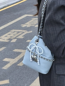 Light blue lychee leather bucket bag with pearl bow and silver chain strap on model