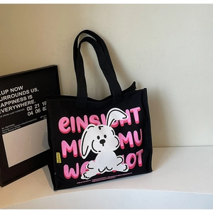 Detail of black canvas tote bag featuring cute cartoon rabbit and pink letter print