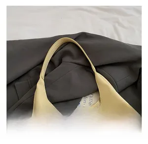 Detail showing smooth integrated handle and premium lychee texture leather on cream tote bag