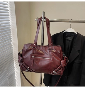 Detail of vintage burgundy tote bag with metal buckles and rivet decorations