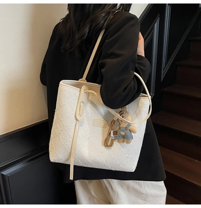 Dettaglio della borsa shopper bianca con trama floreale 3D e ciondolo a forma di orso
