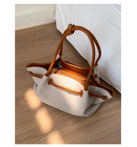 Detail of canvas tote bag with brown leather trim and golden metal zipper pocket