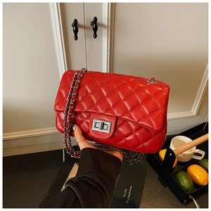 Close-up of a red quilted chain bag with silver twist lock on a minimalist lifestyle setting