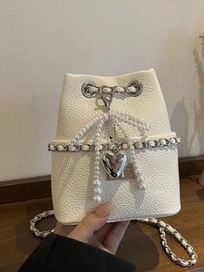 White lychee leather bucket bag with pearl bow, silver heart charm and chain strap