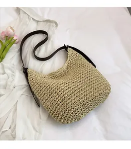 Détail du sac seau en paille tressée avec bandoulière en cuir brun et décor de tulipe