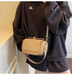 Detail of stylish two-tone beige and coffee leather crossbody bag with metal buckle