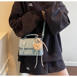 Détail du sac bandoulière bleu clair avec étoiles et pendentif ours en peluche