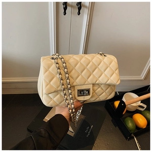 Detail of beige quilted faux leather bag featuring silver chain strap and metal turn-lock
