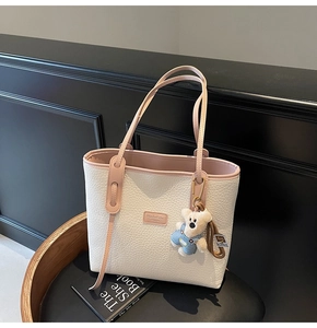Detailed texture of white lychee grain tote bag with pink handles and plush bear charm