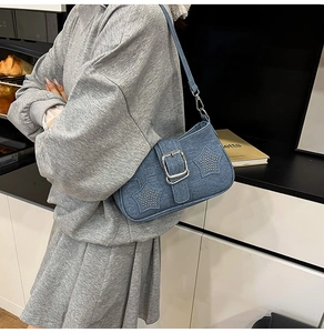 Detail of vintage blue denim shoulder bag with metal buckle and star rivet accents