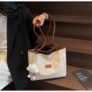 Detail of beige floral jacquard tote bag with dark brown woven handles and plush charm