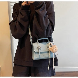 Détail du sac à bandoulière bleu clair avec boucles étoiles et porte-clés ours peluche