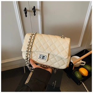 Detail of beige quilted faux leather crossbody bag with silver chain strap and metal lock