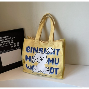 Close-up of yellow canvas tote bag with white cartoon rabbit and blue letter prints