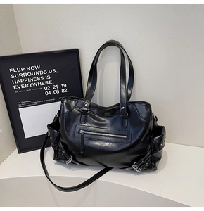 Detail of black faux leather motorcycle tote bag with metallic buckles and zipper pockets