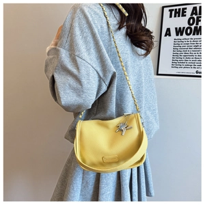 Detail of yellow lychee texture leather handbag with silver chain and horse pendant