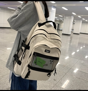 Détail du sac à dos en nylon blanc cassé avec poche filet et boucles de serrage latérales