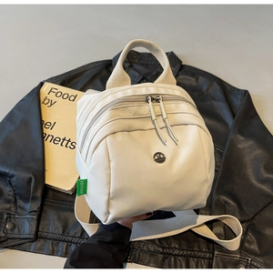 Close-up of off-white backpack featuring Kefer label and dual zippers on leather jacket