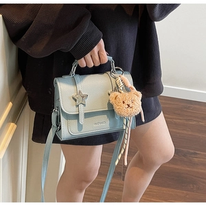 Détail du sac à bandoulière bleu clair avec boucle étoile et pendentif ours en peluche