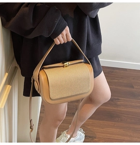 Detail of contrast stitching textured woven flap and gold twist lock on stylish handbag