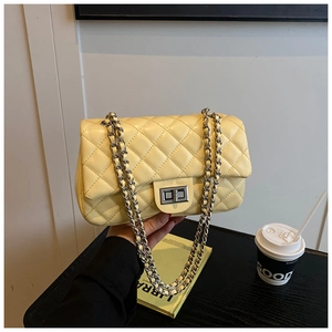 Close-up of yellow quilted crossbody bag with silver chain strap and metal turn-lock