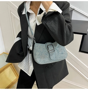 Detail of light blue denim shoulder bag with sparkling rhinestone star and metal buckle strap