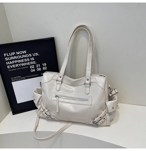 Detailed close-up of cream white faux leather tote bag with silver zippers and buckles