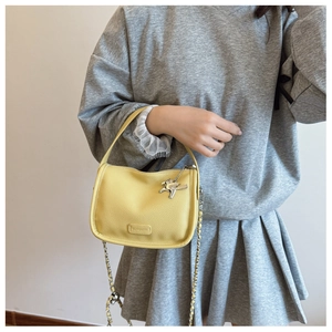 Detail of yellow lychee leather mini square bag with silver metal horse charm and chain