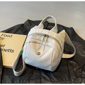 Detail of off-white nylon bag with cute cat ear design and metal M logo on the front