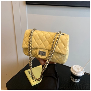 Detail of yellow quilted leather crossbody bag with silver chain strap and metal lock