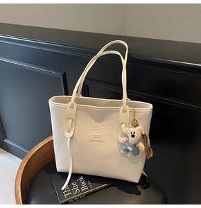 Close-up of white lychee texture leather tote with bear charm and MashaKeke label