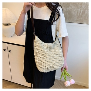 Détail d'un sac seau tissé beige avec bandoulière en cuir marron foncé sur un modèle