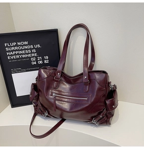 Detail view of burgundy tote bag showing oily faux leather texture and zip pockets