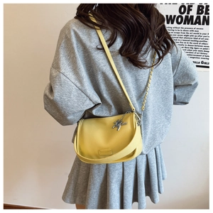 Detail of yellow lychee leather crossbody bag with silver horse charm and chain strap