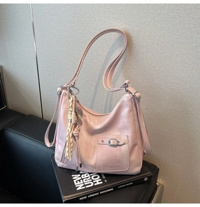 Detailed macro view of pink leather tote bag showing silver zipper and braided fringe charm