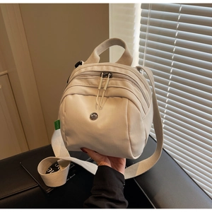 Close-up of cream canvas shell bag featuring durable nylon handles and dual zipper compartments