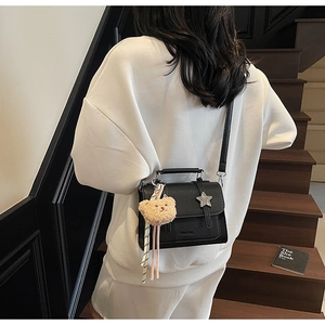Détail du sac bandoulière en cuir grainé noir avec étoile argentée et breloque ours