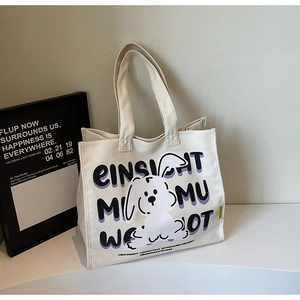 Detail of off-white canvas tote bag with purple typography and cartoon rabbit illustration