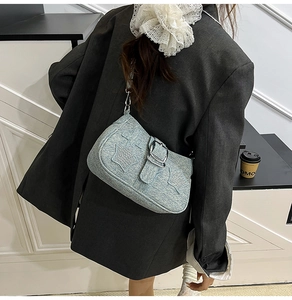 Detail of light blue denim underarm bag featuring sparkling star accents and silver buckle