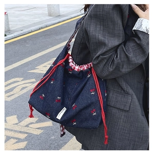 Detail of navy canvas bucket bag with cherry pattern and red gingham lining