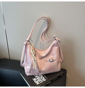 Detail of pink Hobo tote showing leather texture, woven charm, and brand logo