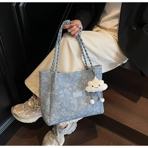 Detail of light blue floral tote bag with woven handles and a cute cloud charm accessory