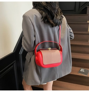 Detail of red leather shoulder bag with beige woven flap and gold metallic clasp closure