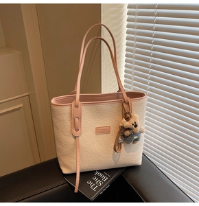 Detail of cream tote bag with lychee texture, pink handles and a cute bear charm