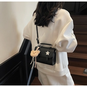 Détail du sac bandoulière en cuir noir avec étoile argentée et breloque ours en peluche