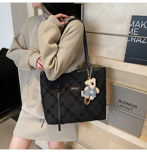 Dettaglio borsa shopper trapuntata nera con ciondolo a forma di orso ed etichetta logo