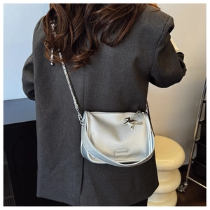 Silver mini crossbody bag with litchi texture and chain strap shown on blazer