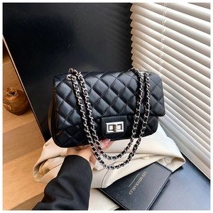 Detail of black quilted chain bag with silver twist lock and glossy leather texture