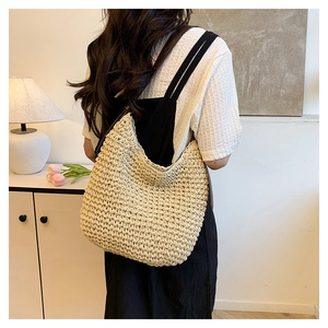 Vue arrière du mannequin portant un sac seau en paille beige dans un décor intérieur
